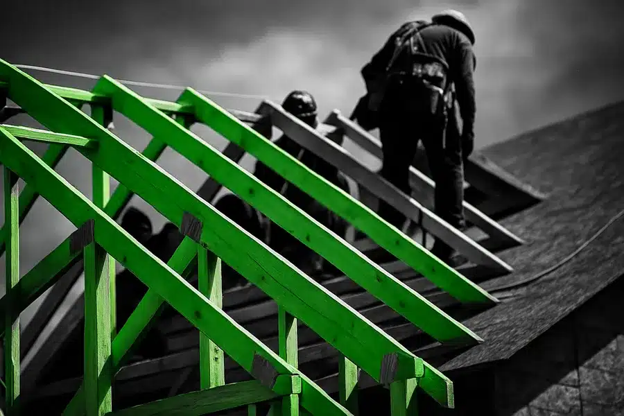 Construction workers on a residential roof, building frame in foreground.