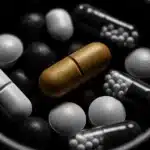 A bowl filled with various colorful pills including capsules and tablets.