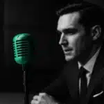 Man speaking into a vintage microphone in a media studio.