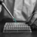 Laboratory technician using a pipette with a microplate.