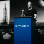 SpaceX presentation with rocket imagery and audience.