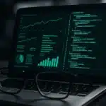 A pair of glasses in front of laptop screens displaying programming code and data visualizations.
